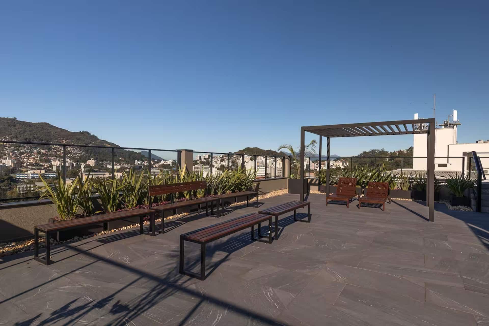 Terraço do prédio com bancos e vista para os morros