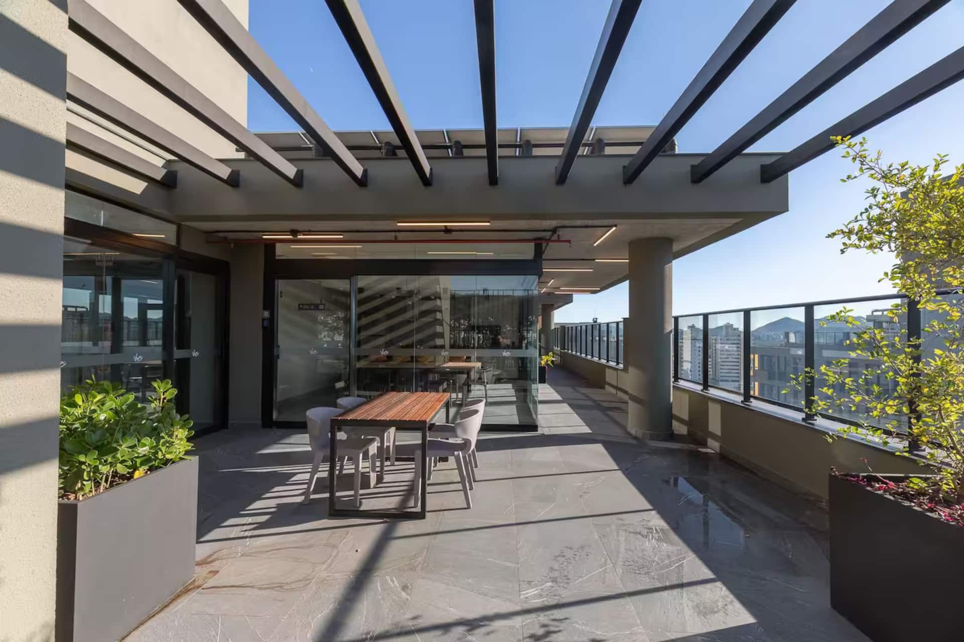 Área com pergolado e mesas no terraço do prédio